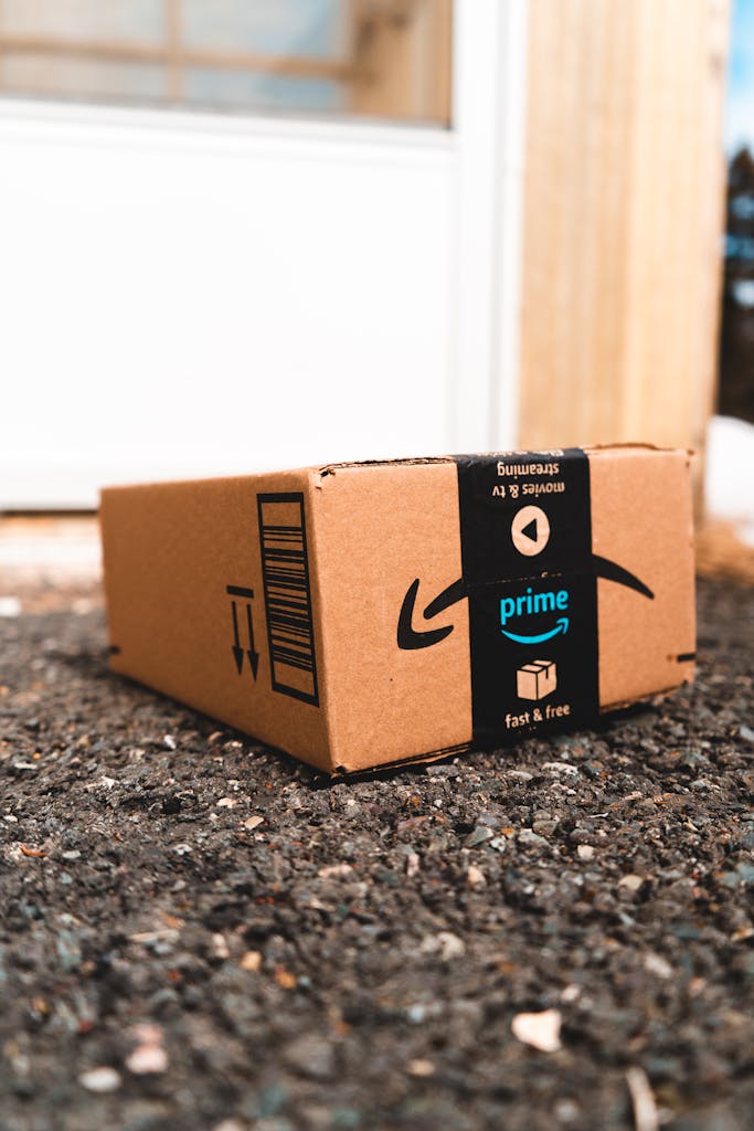 A cardboard box marked with Prime logo placed outside on a porch, ready for delivery.