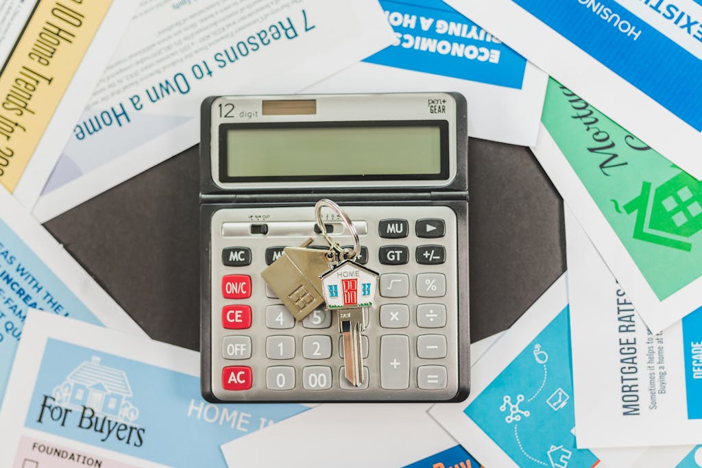 Calculator with keys and real estate documents symbolizes home buying finances.