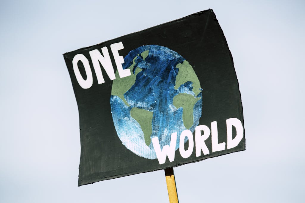 Close-up of a protest sign with Earth and 'One World' text, symbolizing climate change awareness.