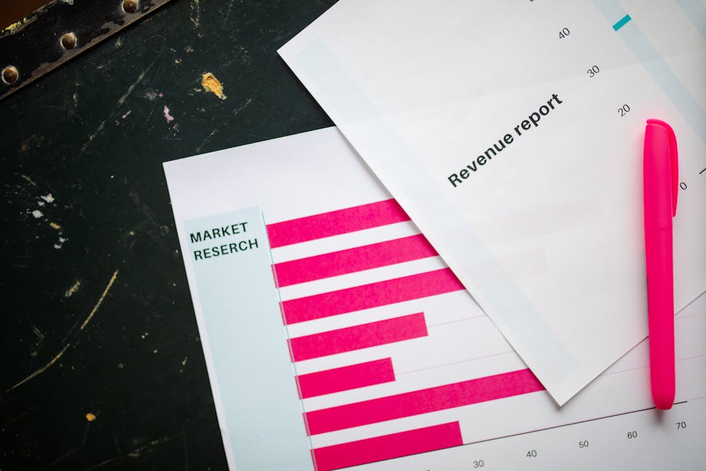 Close-up of market research charts and a revenue report with a pink pen on a desk.