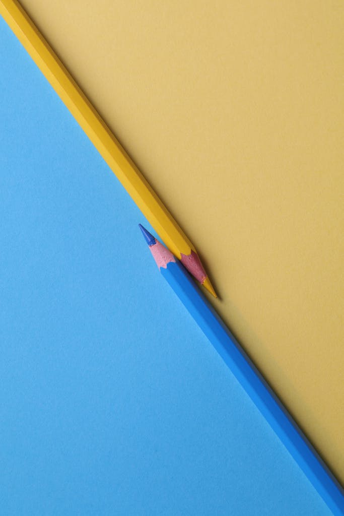 Close-up of vibrant yellow and blue colored pencils on contrasting paper backgrounds.