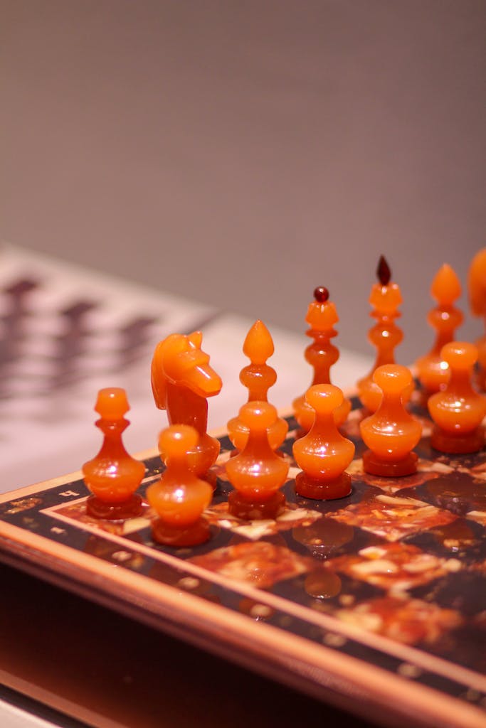 Detailed view of ornamental amber chess pieces arranged on a chessboard.