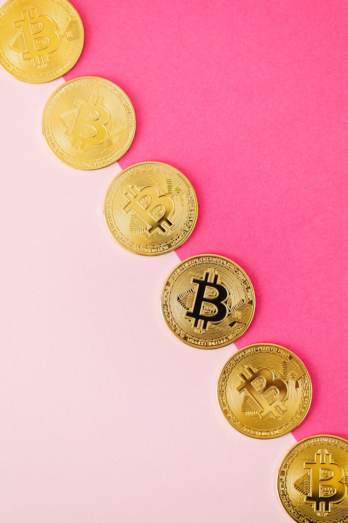 Golden Bitcoin coins arranged on a vibrant pink surface, showcasing cryptocurrency and finance themes.