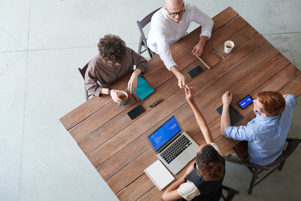 High angle view of a collaborative team meeting in an office setting with laptops and coffee.