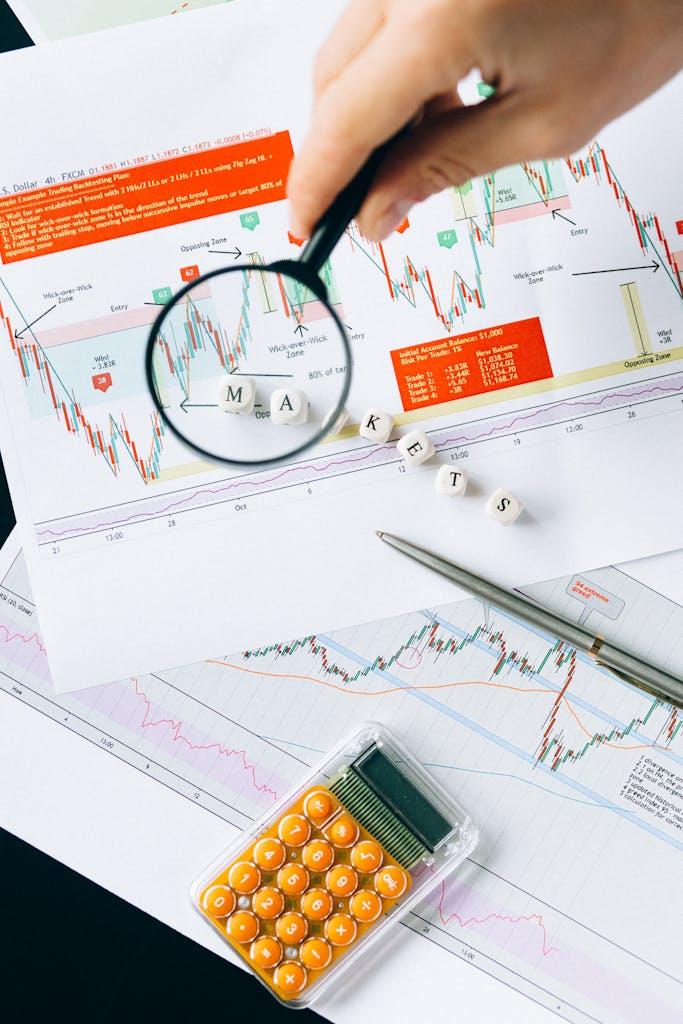 Magnifying glass focusing on market data and charts indicating financial analysis concept.