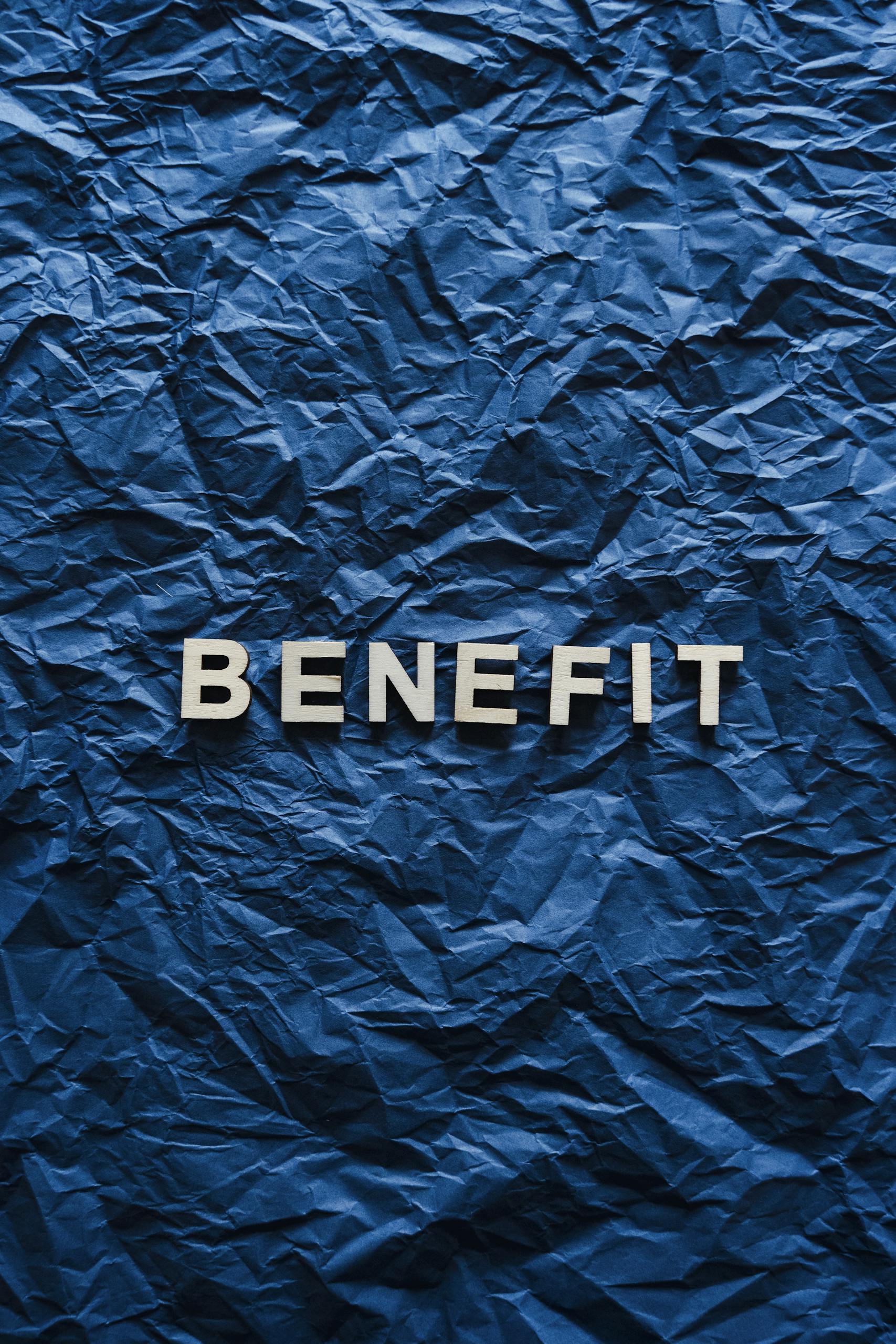 The word 'Benefit' displayed on crumpled blue paper, ideal for concepts.