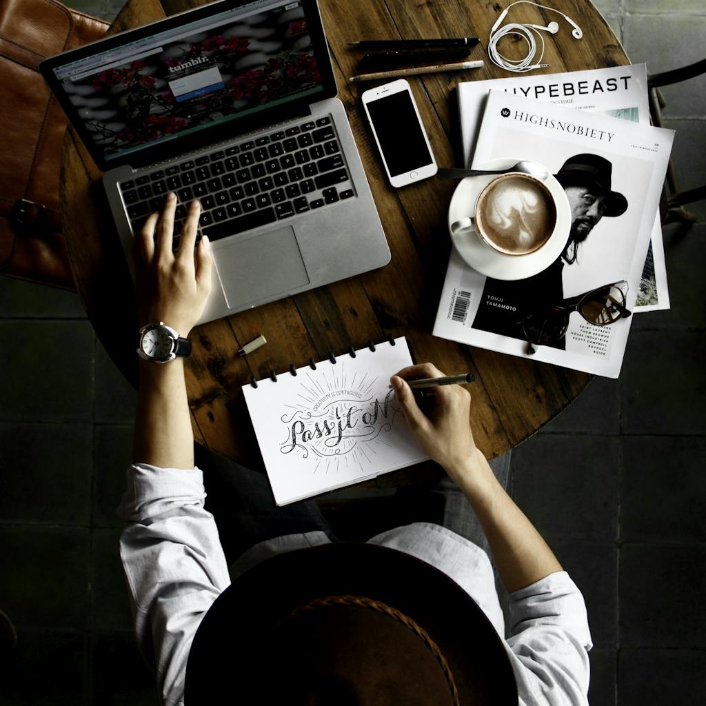 Top view of a creative workspace with laptop, coffee, and hand lettering for design inspiration.