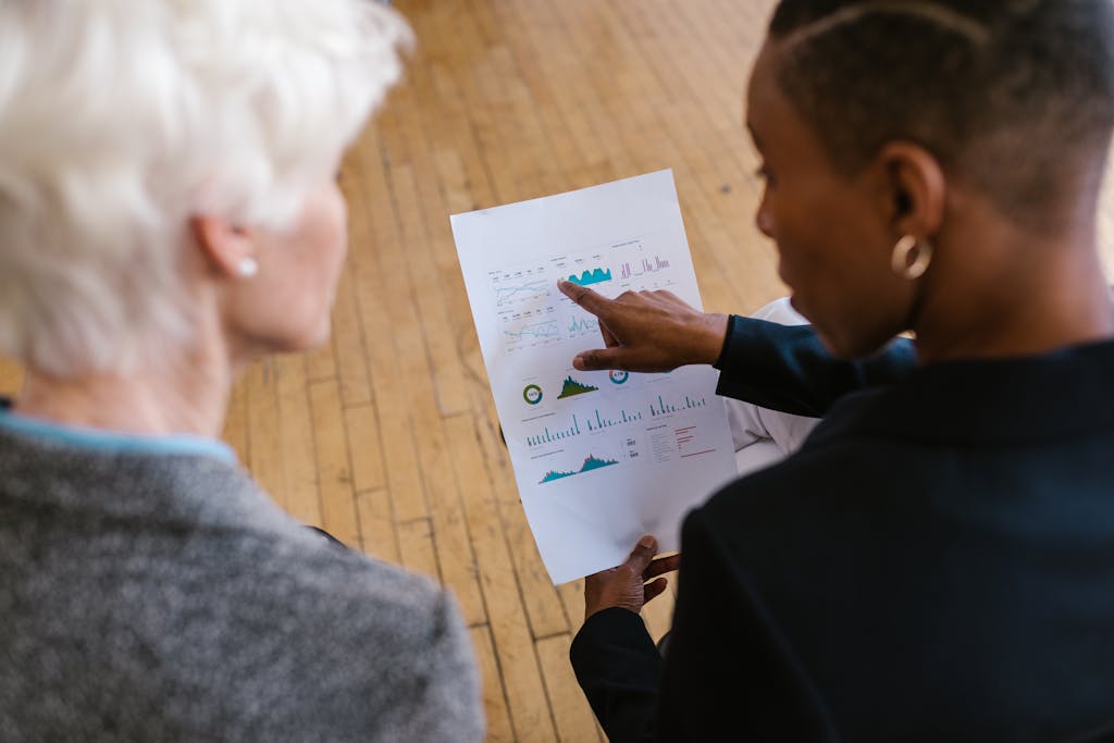 Two professionals reviewing business documents with graphs in an office setting.