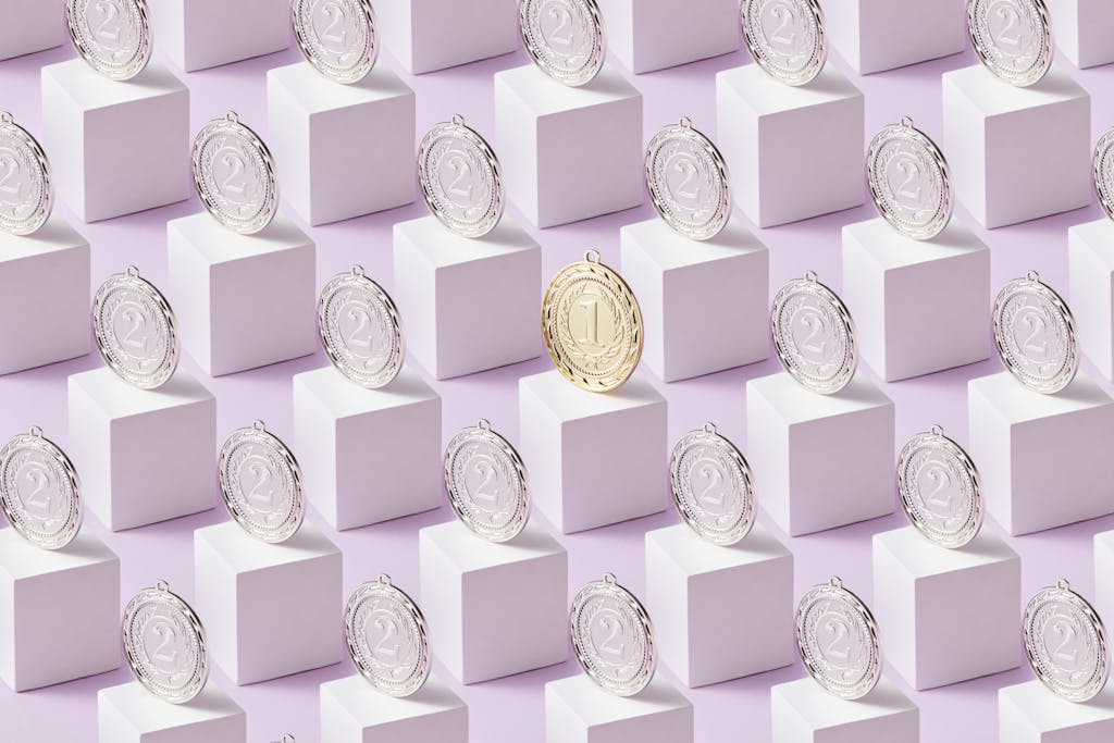 A gold medal stands out among silver medals on white cubes, showcasing uniqueness.